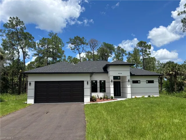 Prairie-style house featuring a front lawn, asphalt driveway, roof with shingles, an attached garage, and stucco siding