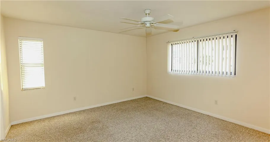 Unfurnished room featuring carpet, healthy amount of natural light, and a ceiling fan