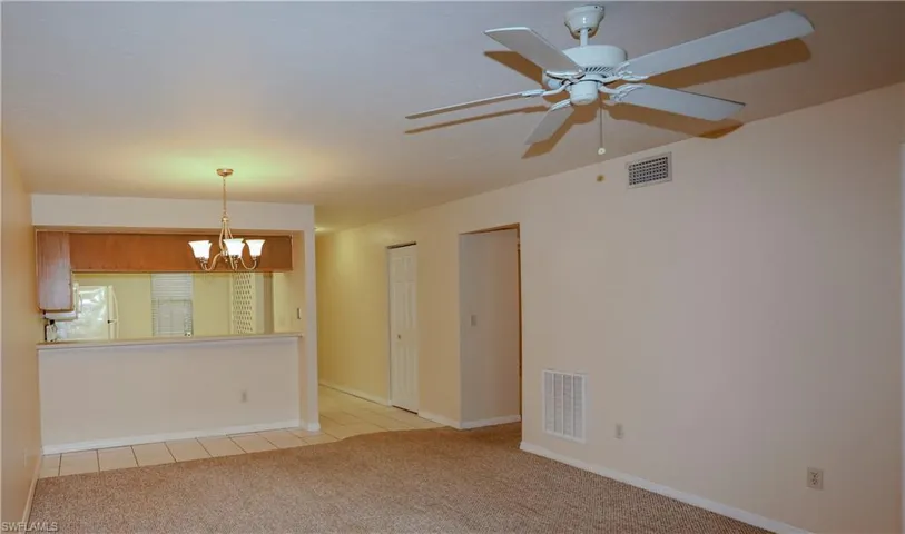 Unfurnished room with a chandelier, light carpet, and light tile patterned flooring