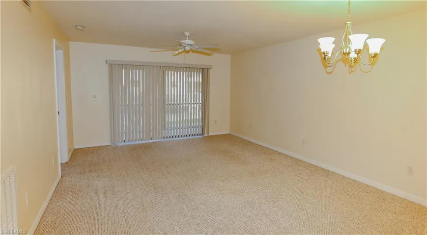 Unfurnished room with light carpet, a ceiling fan, and a chandelier