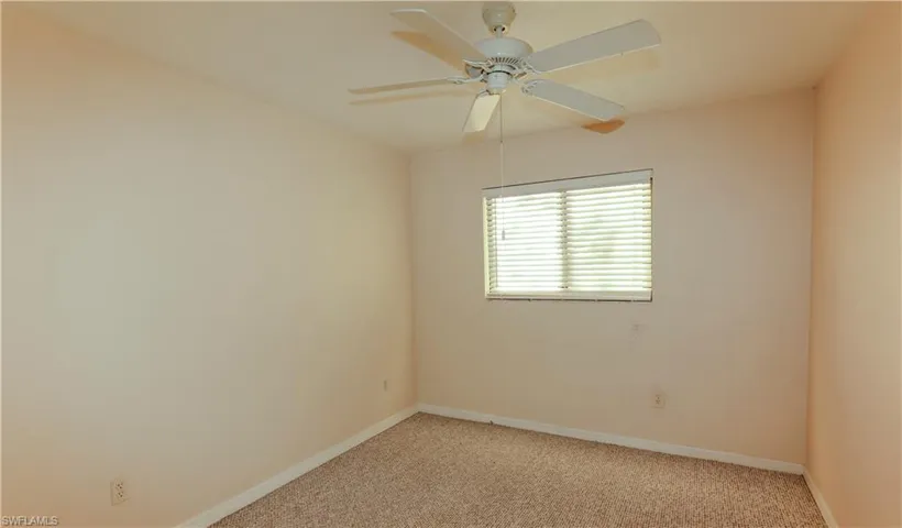 Empty room featuring light colored carpet and ceiling fan