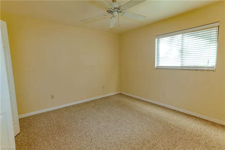 Carpeted empty room featuring baseboards and a ceiling fan