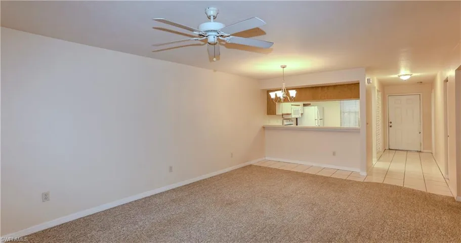 Unfurnished living room featuring light carpet, a chandelier, and ceiling fan