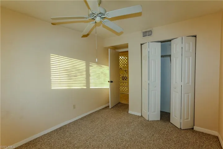 Unfurnished bedroom with carpet, a closet, and a ceiling fan