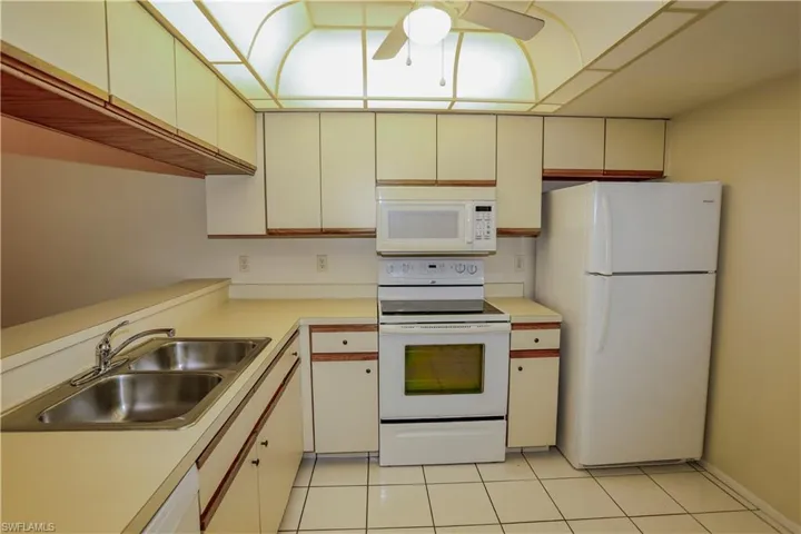 Kitchen featuring white appliances, light countertops, light tile patterned flooring, ceiling fan, and cream cabinets