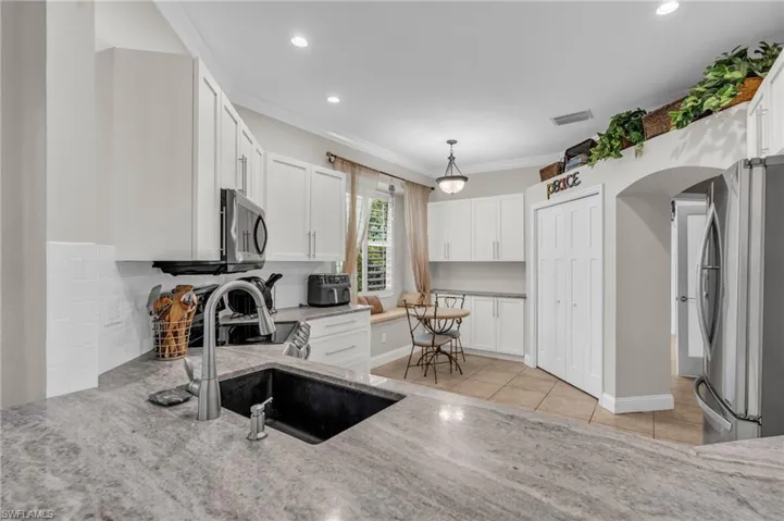 Kitchen featuring appliances with stainless steel finishes, pendant lighting, and white cabinetry