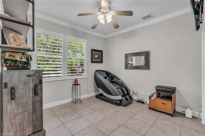 Workout area with crown molding, ceiling fan, and light tile patterned floors