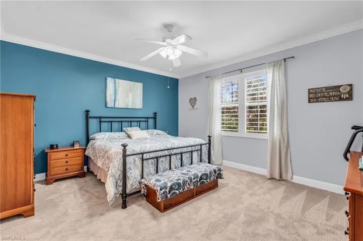Carpeted bedroom featuring ornamental molding and ceiling fan