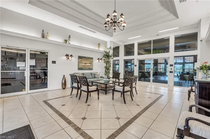Tiled dining space with a raised ceiling, ornamental molding, a high ceiling, and a chandelier
