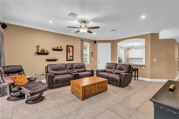 Tiled living room with crown molding and ceiling fan