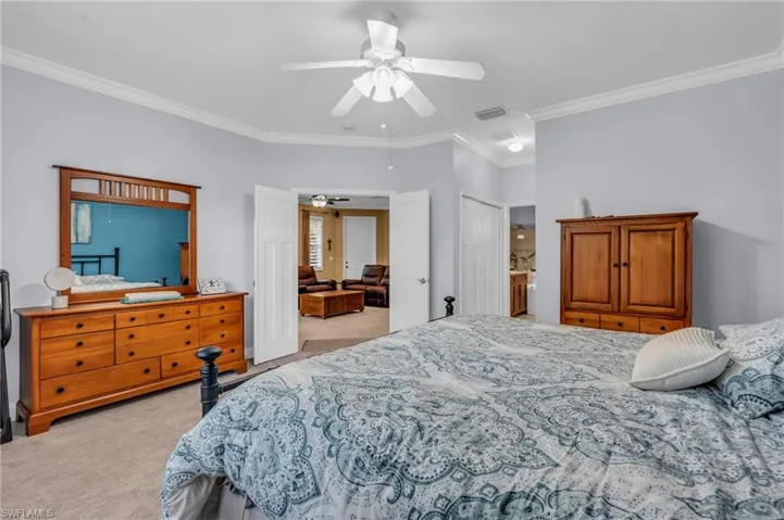 Bedroom featuring crown molding, ceiling fan, a closet, and light colored carpet