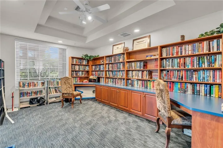 Carpeted office with ceiling fan, a tray ceiling, and built in desk