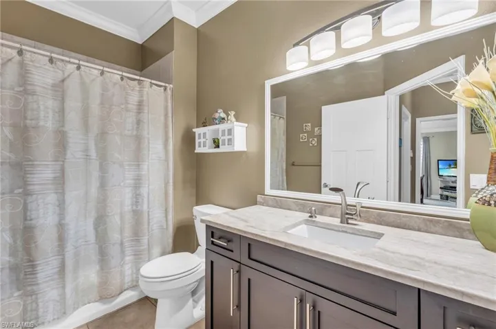 Bathroom with crown molding, vanity, and toilet