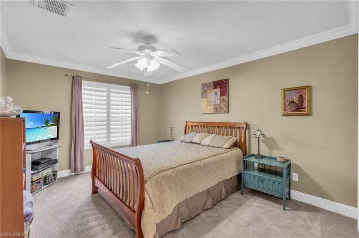 Bedroom featuring light carpet, crown molding, and ceiling fan