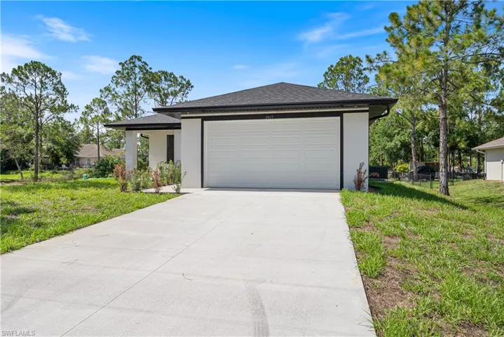 View of front of property featuring driveway, a garage, stucco siding, and roof with shingles
