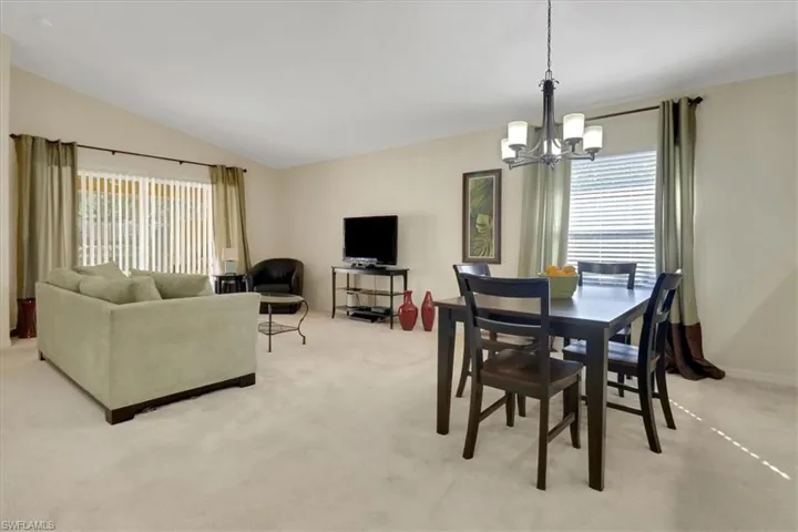 Dining room featuring light carpet, lofted ceiling, and a chandelier