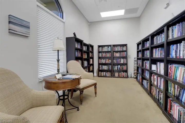 Sitting room featuring light carpet, bookshelves, and a paneled ceiling