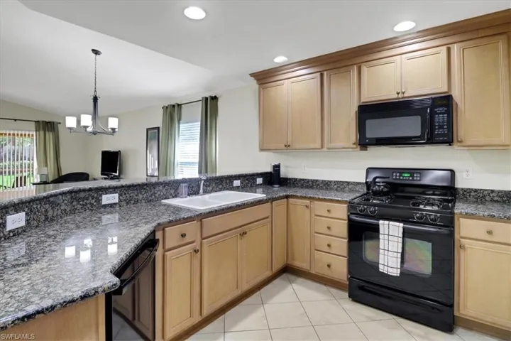 Kitchen with black appliances, recessed lighting, a chandelier, lofted ceiling, and a peninsula