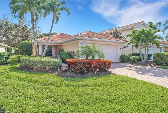 Mediterranean / spanish house with stucco siding, a tile roof, an attached garage, decorative driveway, and a front lawn