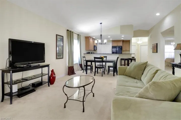 Living room with a chandelier, recessed lighting, vaulted ceiling, and light colored carpet