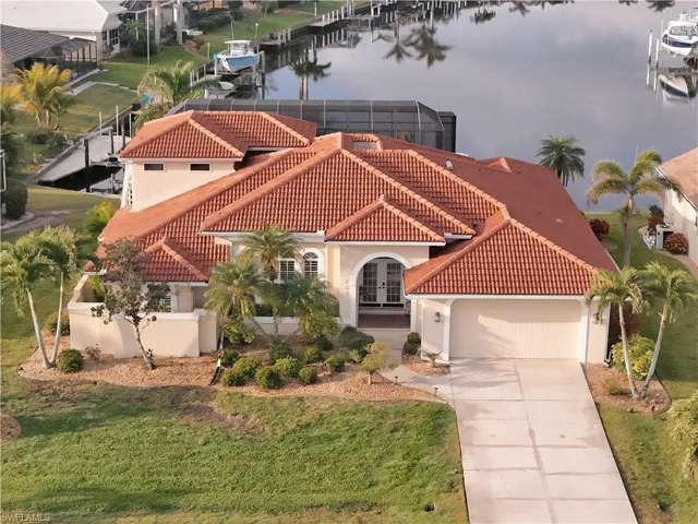 View of front of property with french doors, a front lawn, a water view, a garage, and glass enclosure