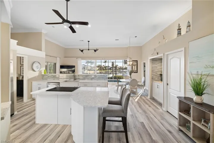 Kitchen with hanging light fixtures, a kitchen island, sink, stainless steel dishwasher, and white cabinets