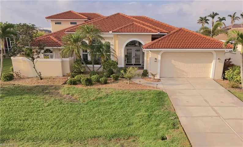 Mediterranean / spanish home with french doors and a front lawn