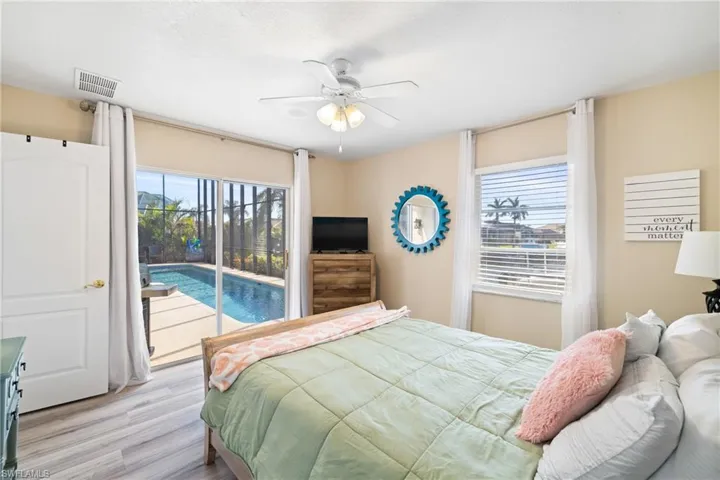 Bedroom with ceiling fan, light wood-type flooring, multiple windows, and access to exterior