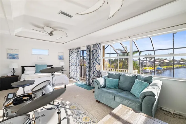 Living room featuring a raised ceiling, a water view, and ceiling fan