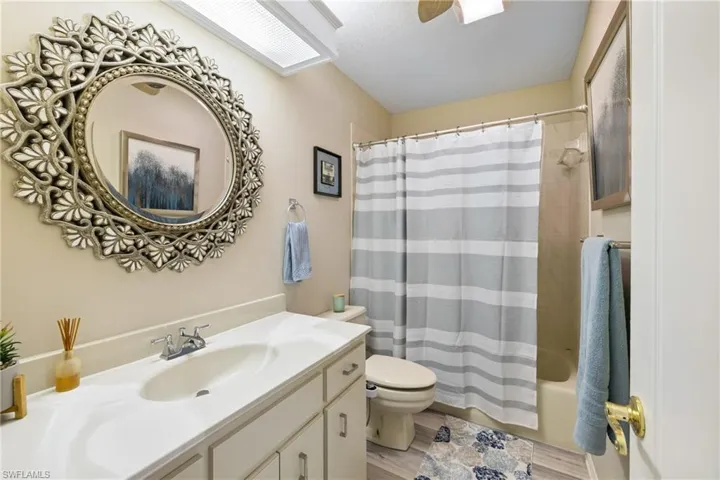 Full bathroom featuring shower / bath combo with shower curtain, wood-type flooring, vanity, ceiling fan, and toilet