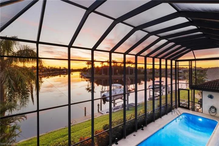 Pool at dusk featuring a water view and a lanai