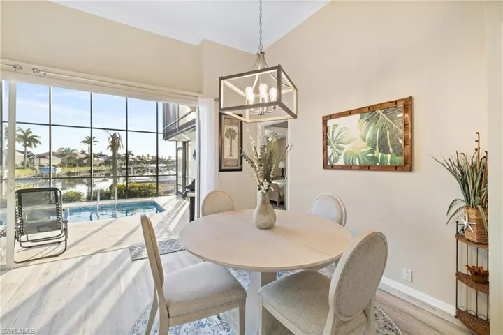 Dining space featuring a water view, an inviting chandelier, wood-type flooring, and ornamental molding