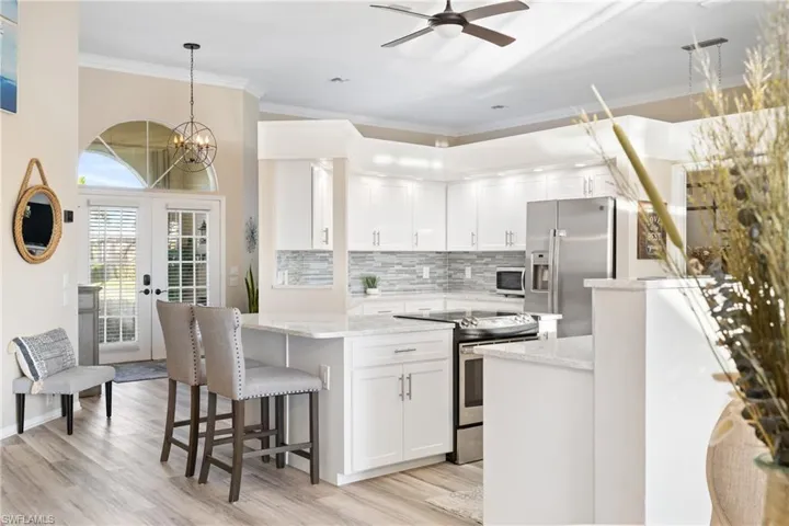 Kitchen with white cabinetry, appliances with stainless steel finishes, light stone counters, and pendant lighting