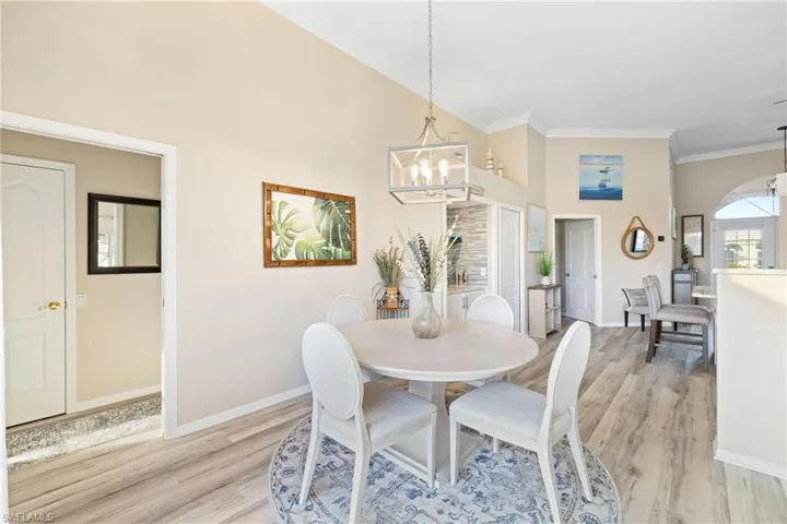Dining room featuring ornamental molding, high vaulted ceiling, an inviting chandelier, and light hardwood / wood-style flooring