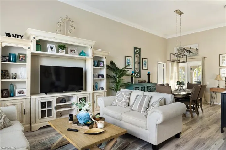 Living room with ornamental molding, a towering ceiling, a notable chandelier, and light hardwood / wood-style flooring
