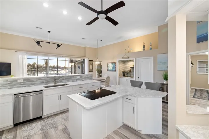 Kitchen featuring sink, white cabinetry, a kitchen island, black electric stovetop, and stainless steel dishwasher