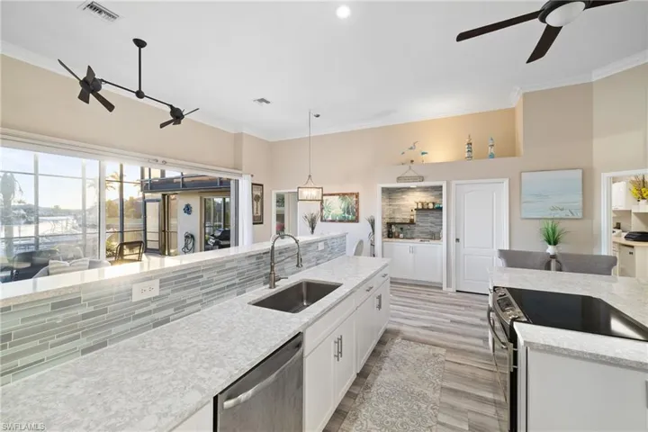 Kitchen with appliances with stainless steel finishes, sink, white cabinetry, pendant lighting, and ceiling fan