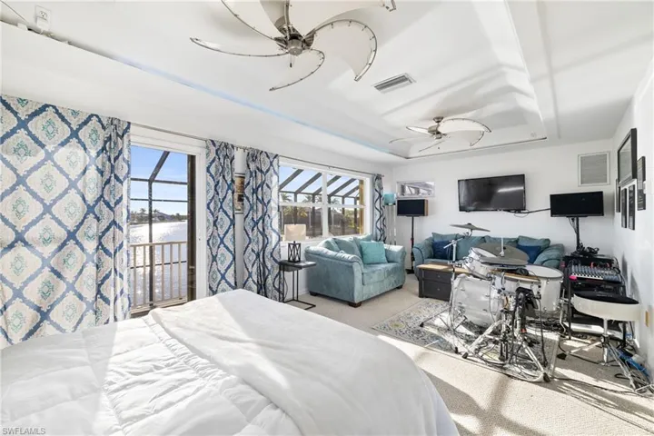 Carpeted bedroom featuring ceiling fan, a tray ceiling, and access to outside