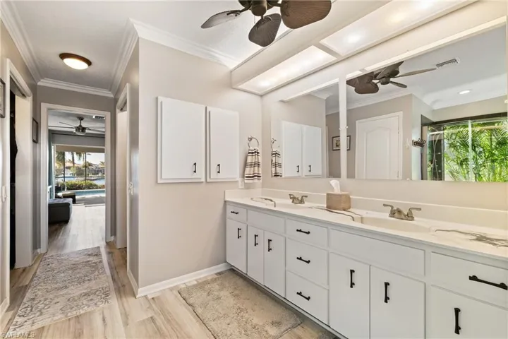 Bathroom with hardwood / wood-style floors, ceiling fan, crown molding, and vanity