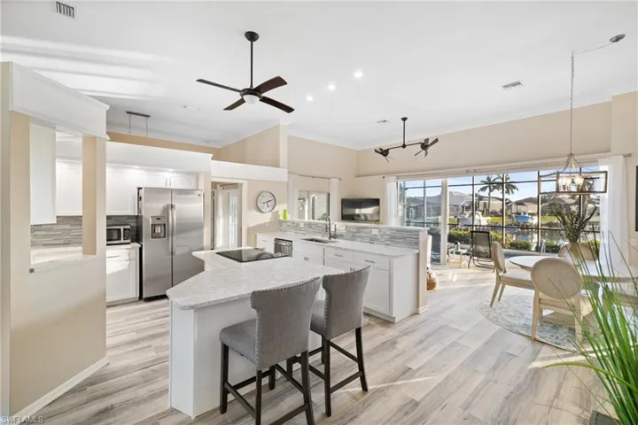 Kitchen with kitchen peninsula, stainless steel appliances, sink, light stone counters, and white cabinets