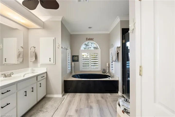 Bathroom with ceiling fan, shower with separate bathtub, crown molding, hardwood / wood-style floors, and vanity