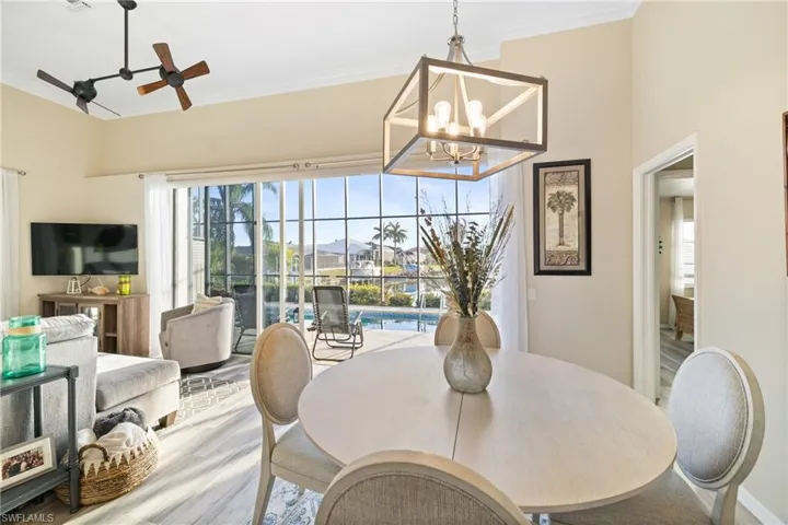 Dining space with ceiling fan with notable chandelier, crown molding, and wood-type flooring