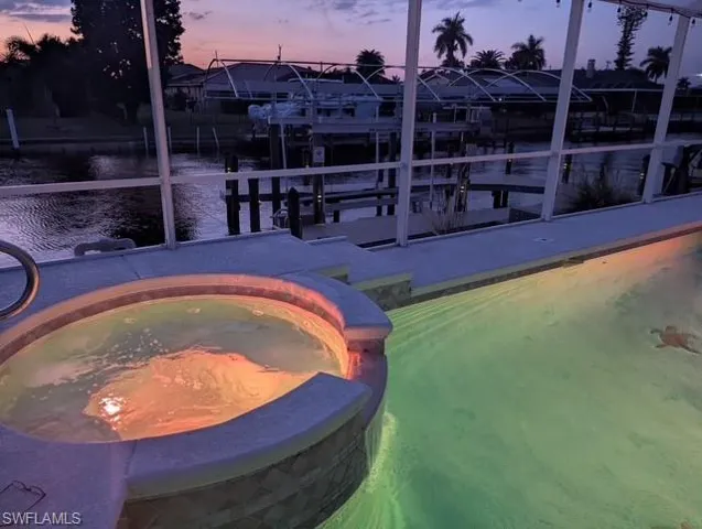 View of pool featuring a pool with connected hot tub, a water view, and boat lift