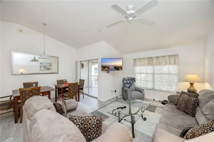 Living room with healthy amount of natural light, lofted ceiling, wood finished laminate floors, and a ceiling fan