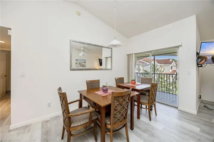 Dining area with lofted ceiling, light wood-style flooring, and a ceiling fan