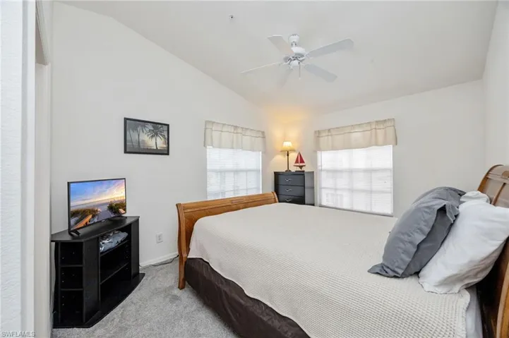 Bedroom with light colored carpet, vaulted ceiling, and a ceiling fan