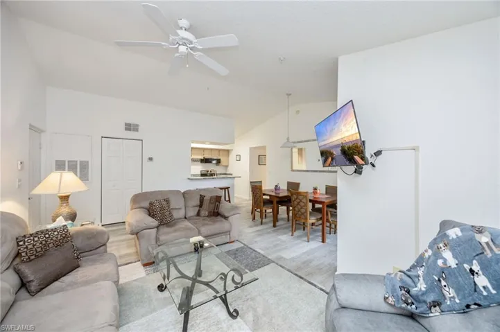 Living area featuring light wood-style floors, ceiling fan, and vaulted ceiling