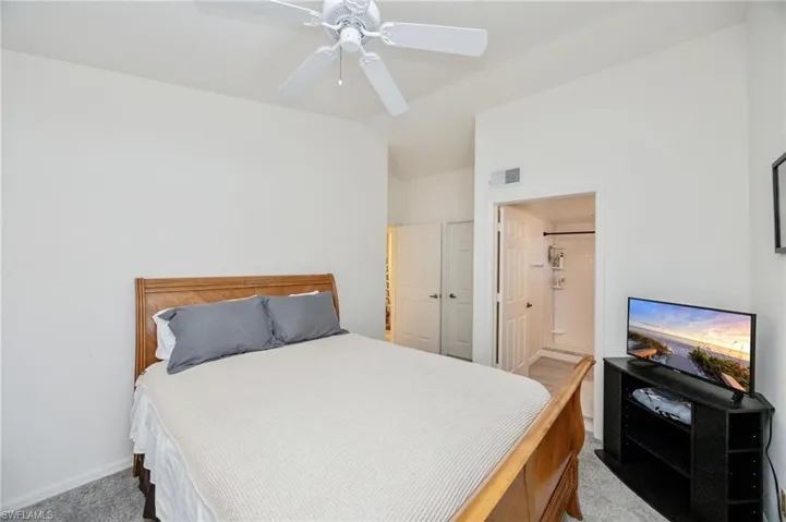 Bedroom with carpet flooring, a ceiling fan, lofted ceiling, and ensuite bathroom