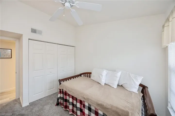 Bedroom with light colored carpet, ceiling fan, and a closet