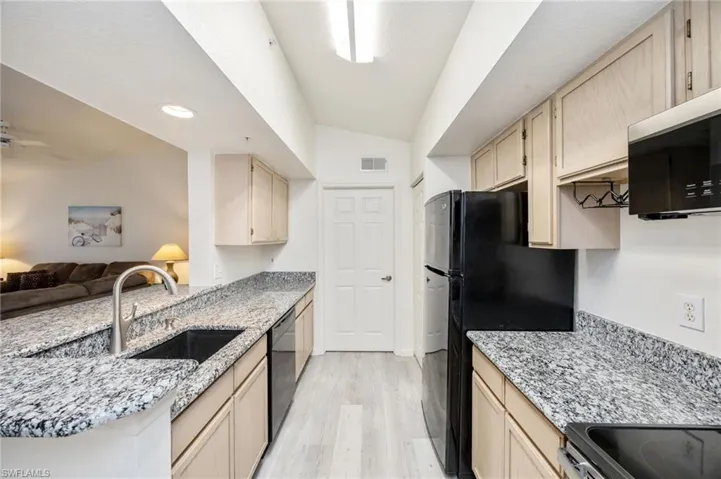 Kitchen featuring light stone countertops, light wood finish cabinets, a peninsula, light wood-style floors, and recessed lighting